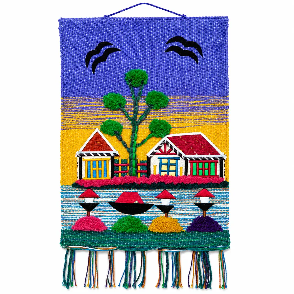 Handmade wall hanging with two cottages, a tufted tree, boat and lamp posts on a purple and yellow sky