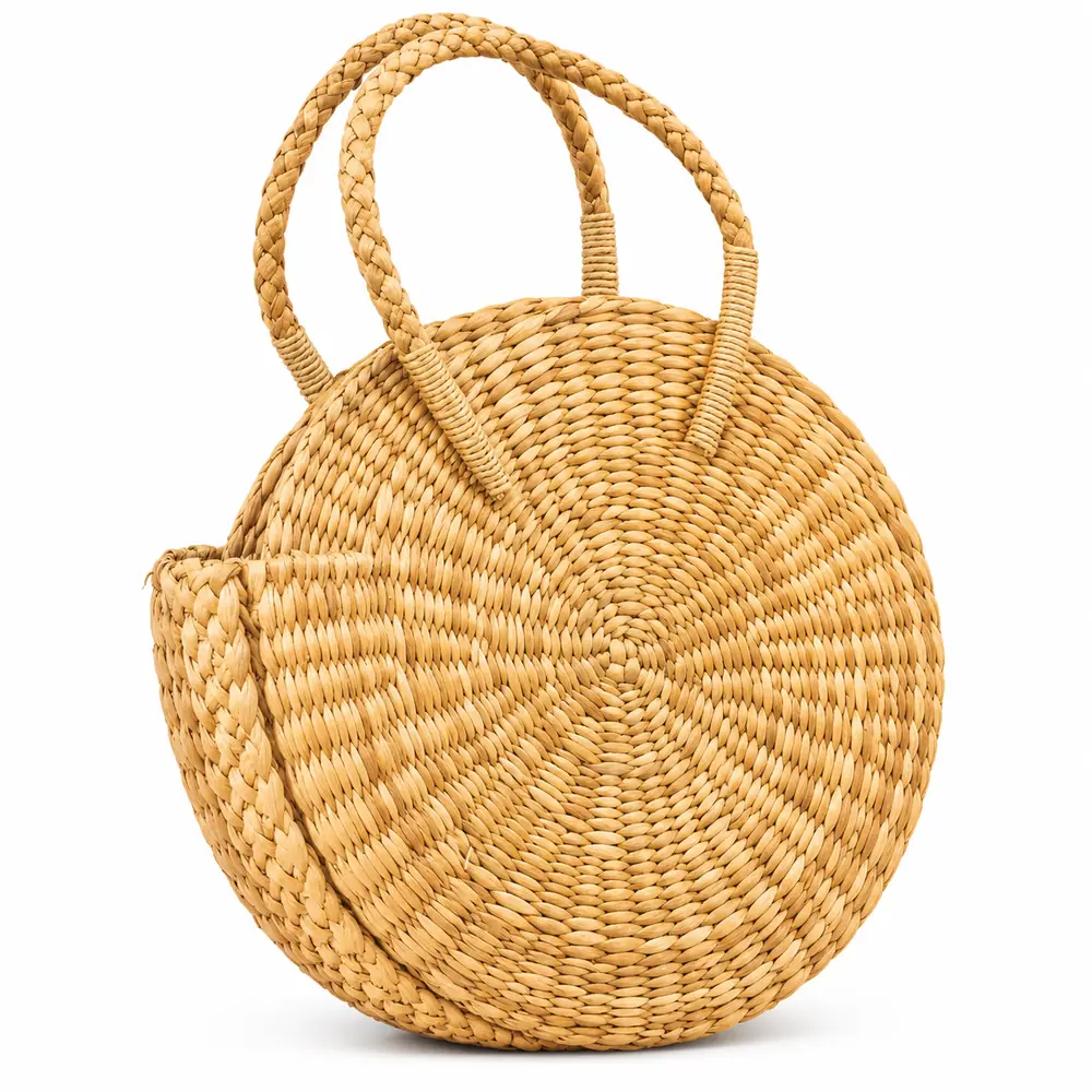 Side view of a round grass basket bag with braided handles and woven side gusset
